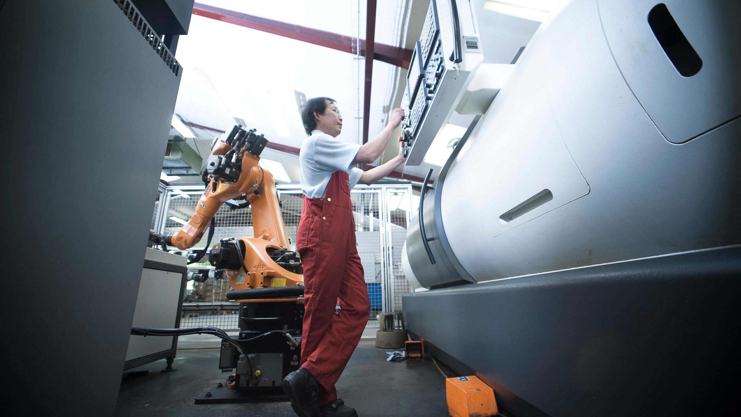 Production worker operating a metal processing machine at the factory in Denmark